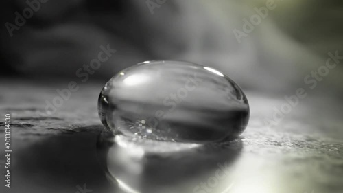Mesmerizing close-up of a water droplet reflecting light and surrounded by ethereal smoke in a dark environment
