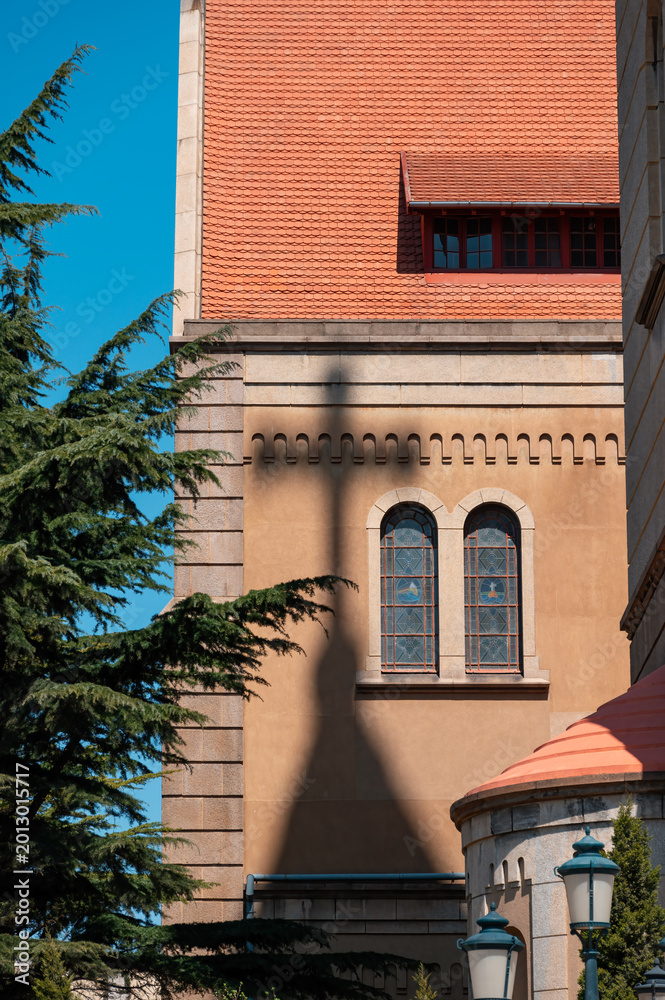 Fototapeta premium The spire of the cross casts a shadow on the exterior of the church building in Qingdao, China