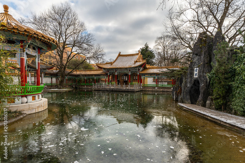 View of Chinese Garden in Zurich during winter with a traditional pagoda, bridge, and frozen pond