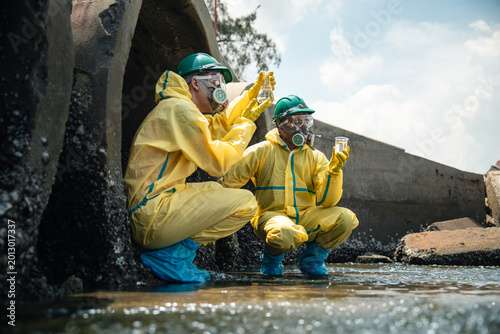 Environmental Workers Discussing Wastewater Sample Findings While Wearing Hazardous Protective Equipment During Coastal Pollution Inspection Process
