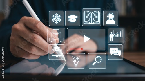 Person using stylus on tablet interacting with digital interface displaying icons for online education video player and communication online learning technology internet connection