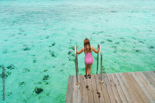 A girl on holiday, ready to dive in the crystal-clear water on a dream island, poster with copy space.