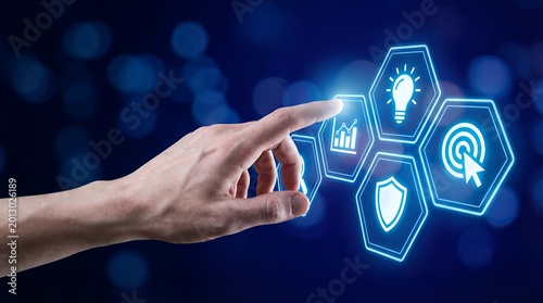 Human hand interacts with glowing blue hexagonal icons representing data analytics innovation security and targeting set against a bokeh blue digital abstract technology interface
