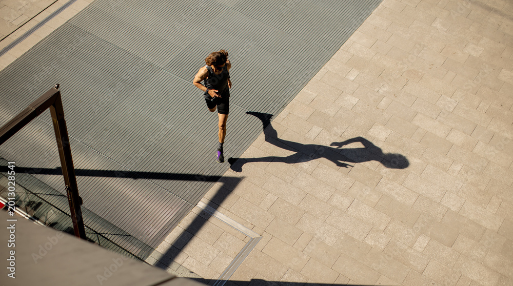 Fototapeta premium Runner moves along the sidewalk in the urban area during daylight hours