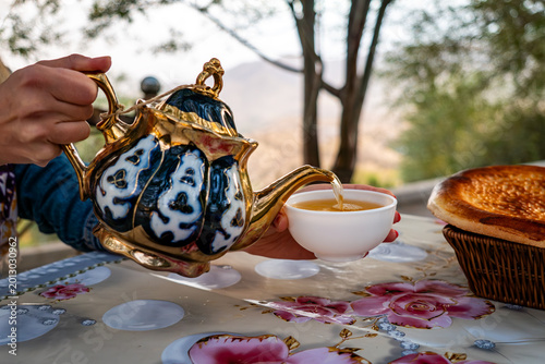 Tableau sur toile woman's hand pours hot tea into a bowl from a teapot