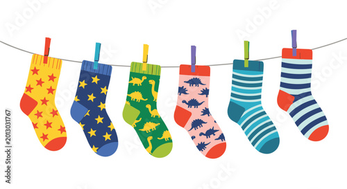 Row of colorful children socks with star, dinosaur, and stripe patterns hanging on a laundry line with multi colored clothespins.