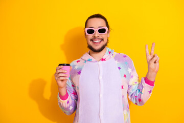 Happy man in colorful pajama hoodie smiles and poses with peace sign for lifestyle and sleepwear stock photo