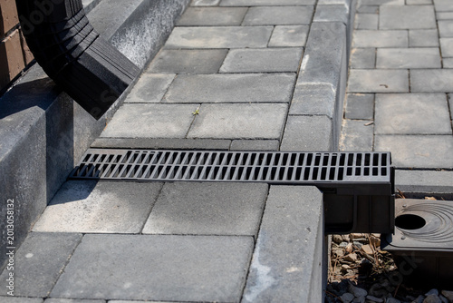 Принти на полотні Linear drainage grate installed between concrete pavers, connected to downspout