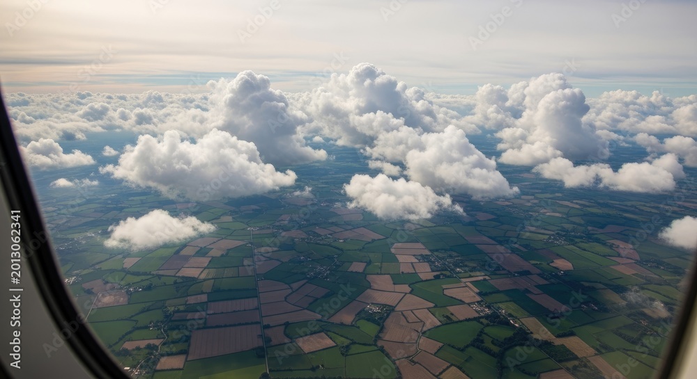 Obraz premium Aerial view of fluffy white clouds above green patchwork fields