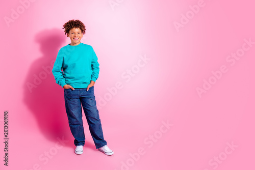 Photos Smiling boy in turquoise sweatshirt standing against a pink background, casual y
