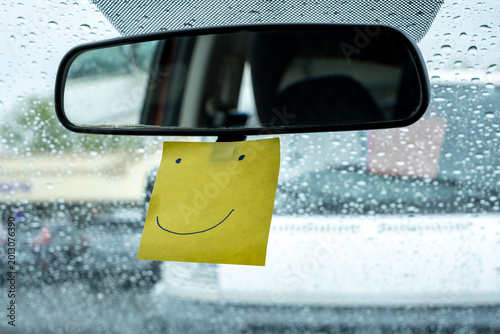 Happy face Sticky Note on car Rearview Mirror During Rain
