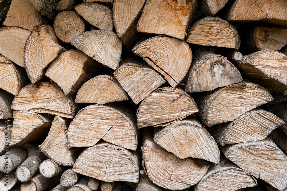Fototapeta premium Stacked logs showing natural wood texture and patterns, ideal for concepts related to woodworking, sustainability, and rustic design environments.