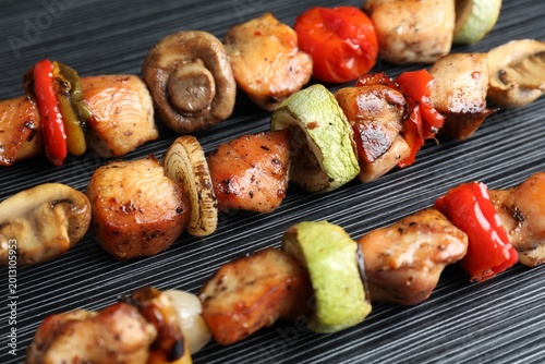 Tableau sur toile Delicious shish kebabs with vegetables on black table, closeup