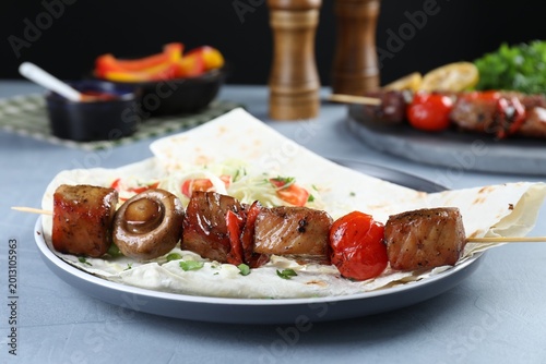 Vászonkép Delicious shish kebab with vegetables served on gray table, closeup
