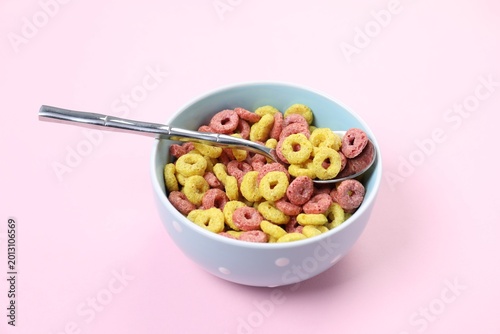Foto Bowl of delicious cereal and spoon on pink background, closeup