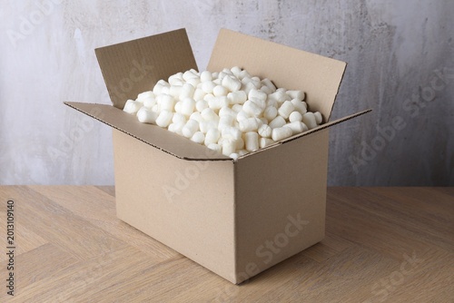 Photos Cardboard box with styrofoam pieces on wooden table