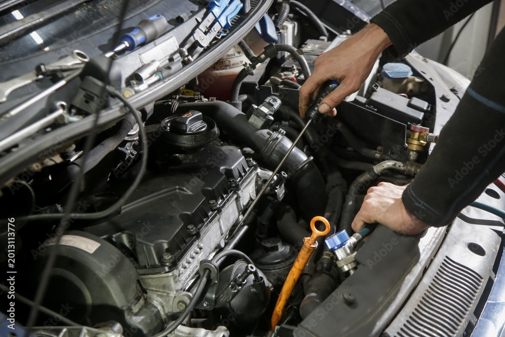 Fototapeta premium Car Maintenance - Mechanic Checking Engine Oil Level Using Dipstick at Workshop