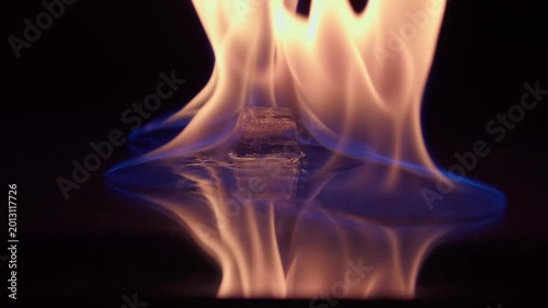 Ice and fire on black background. Ice cube on fire. . Slow motion 