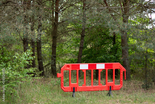Red Plastic Safety Barrier Blocking Access at the Edge of a Dense Forest