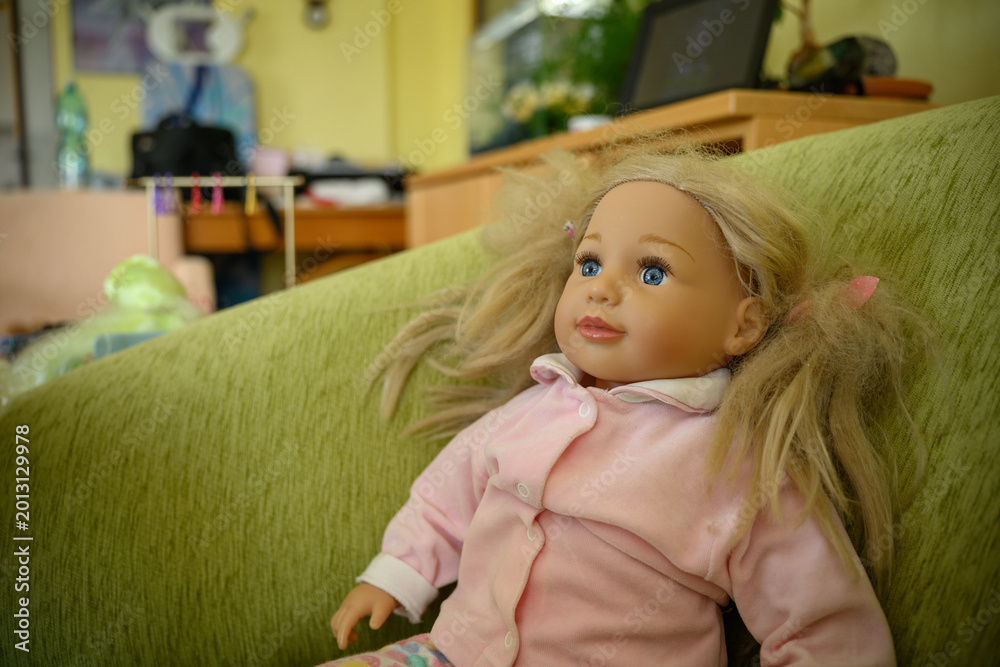 Fototapeta premium Child doll sitting in an armchair in a living room.