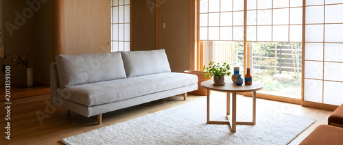 Japanese-style living room featuring a gray sofa, tatami mat, and shoji screens with natural light