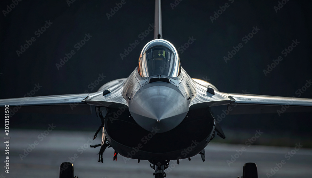 Fototapeta premium Close-up front view of a fighter jet on a dark runway airplane aircraft
