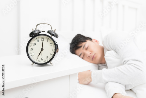 Tableau sur toile Sleeping Man with Alarm Clock in Bright Bedroom