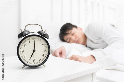 Photos Alarm Clock on Bedside Table with Sleeping Man in Bedroom