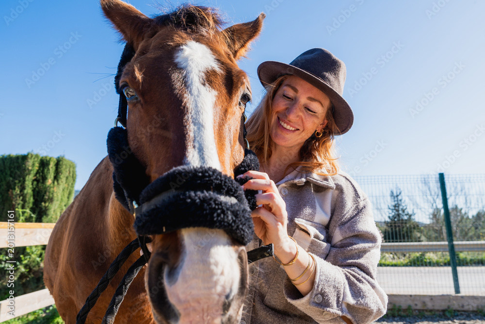 Obraz premium Woman smiling bonding with horse in rural setting
