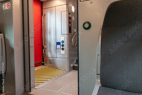 Foto Modern train interior with seat, door connection area and accessibility controls inside passenger carriage