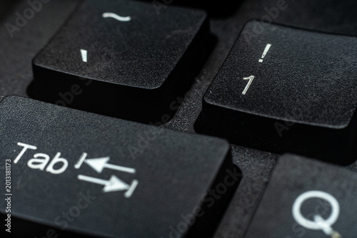 Fotografie Close-up macro of black keyboard keys Tab and number 1 with white lettering, dramatic lighting on textured plastic surface