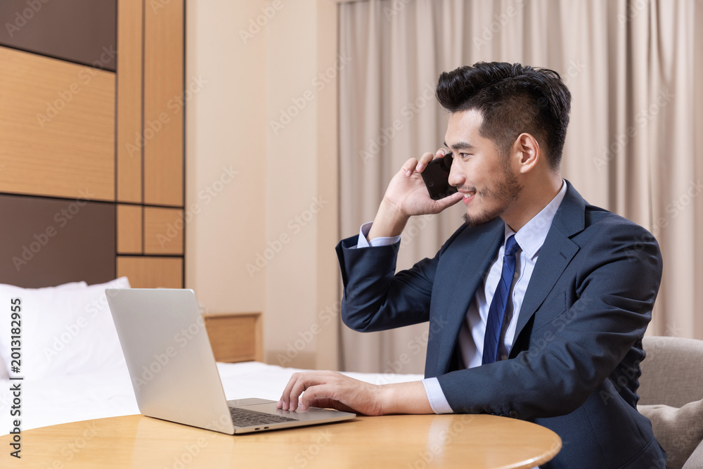 Obraz premium Businessman Working on Laptop and Phone in Hotel Room