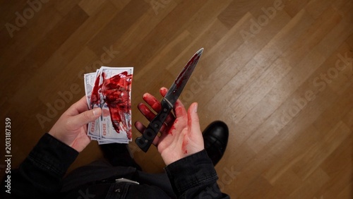Schilderij op canvas Person's hands holding a stack of blood stained cash and a blood covered knife,