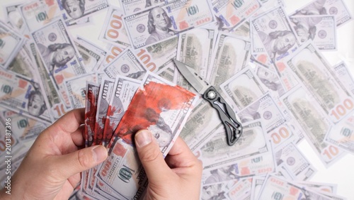 Εκτύπωση καμβά Hands holding several 100 bills splattered with fake blood, symbolizing dirty mo