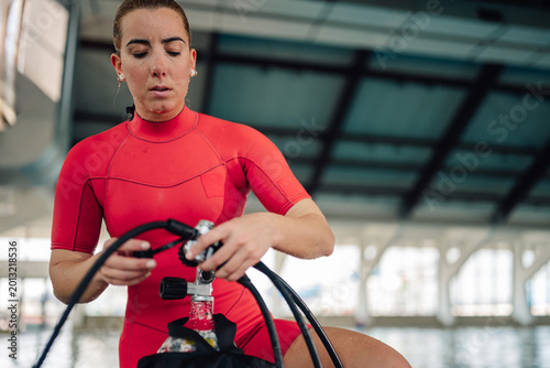 Foto Woman diver in red wetsuit connecting regulator to scuba tank, preparing for und