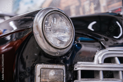 Fotografía Detailed close-up view of front of classic black car, showcasing round headlight with chrome bezel and ribbed smaller light below