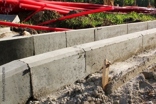 Tableau sur toile Construction site showing concrete curb stones installed in ground with red plas
