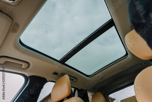 Картината върху платно Interior view of a modern car with a panoramic sunroof showcasing a cloudy sky a