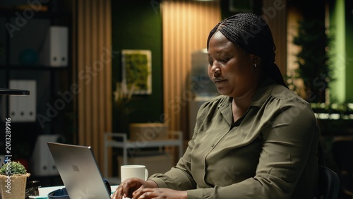 Foto Female worker correcting pose and stretching her neck muscles, leaning back in reclining chair and massaging upper back for muscle relief