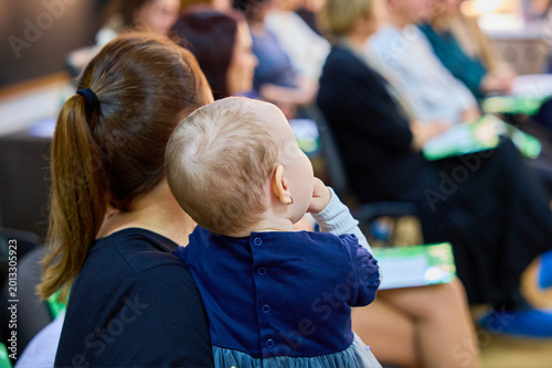 Young caucasian mother with baby attending community event