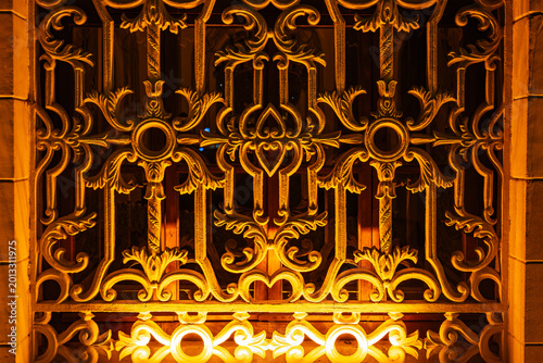 Bild auf Leinwand Ornate ironwork gate illuminated by warm light in evening ambiance