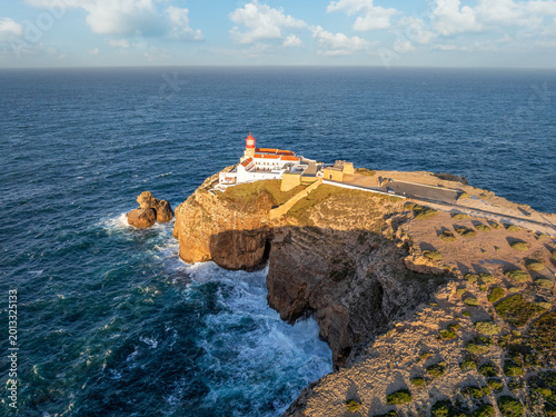 Drone view of the Lighthouse of Cabo de Sao Vicente in Sagres, Algarve, Portugal, at sunrise with Atlantic ocean, cliffs, and aerial sea cliffs