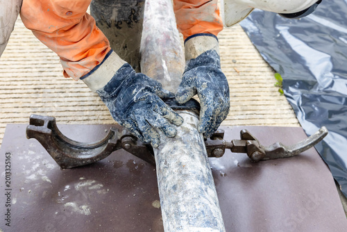 Tableau sur toile Construction worker removing rubber gasket from concrete pumping pipeline during