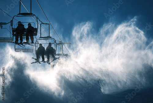 Ski lift ascending through a cloud of snow skiers on lift.