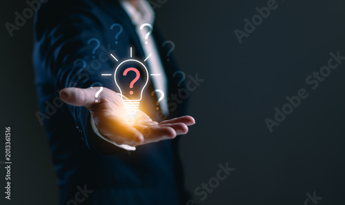 Canvastavla Businessman holding glowing question mark light bulb, symbolizing creative probl