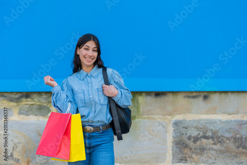 Young woman smiling carrying shopping bags and backpack