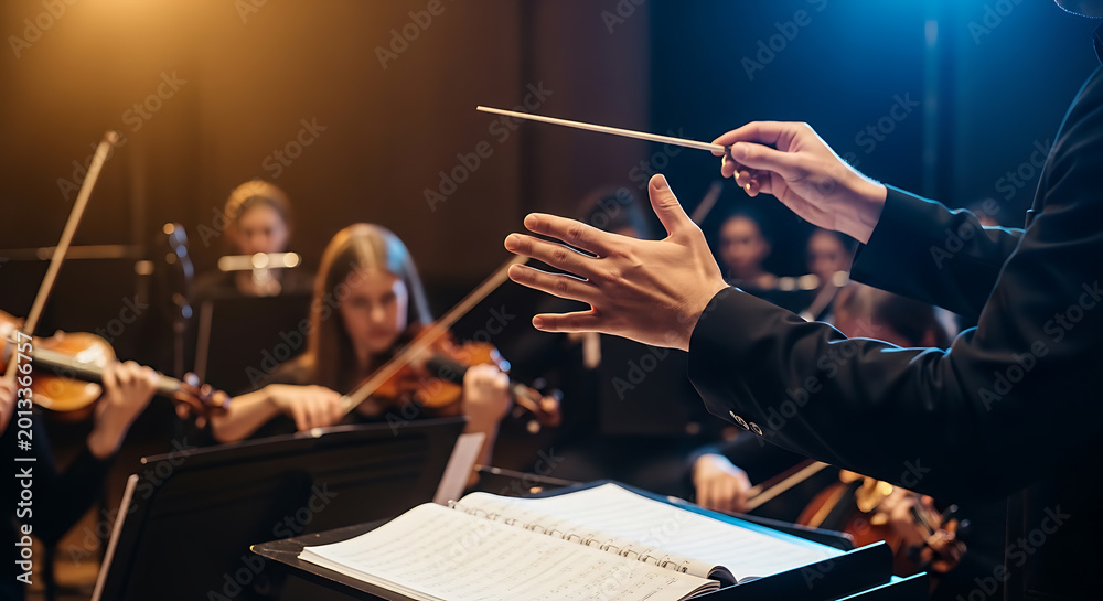 Fototapeta premium Conductor's hands with a baton leading an orchestra during a musical performance or rehearsal.