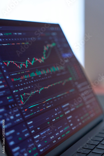 Stock market chart displayed on laptop screen on dark desk