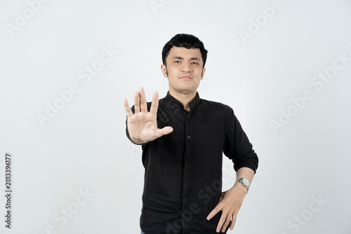 Young Asian man showing stop gesture with palm facing camera on white background
