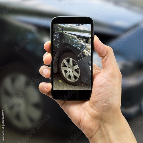 Person holding smartphone showing damaged car tire on screen